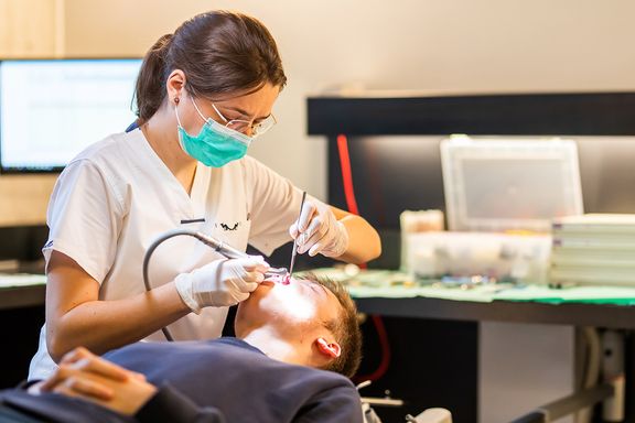 Orthodontist werkt in de mond van een patiënt.